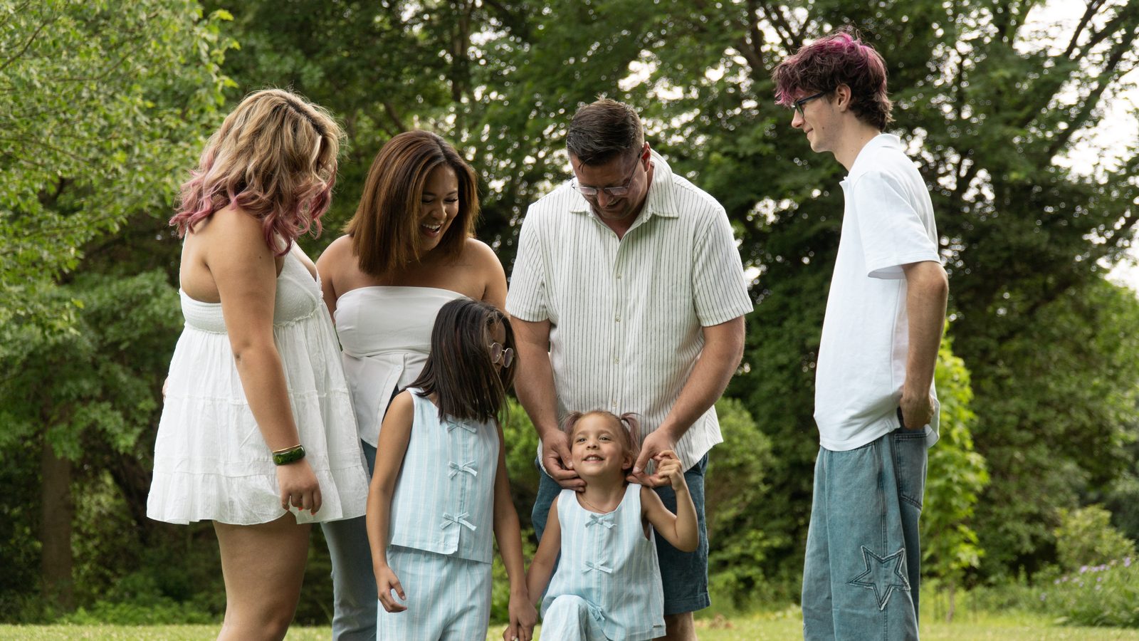 Family of six laughing together on a summer lawn
